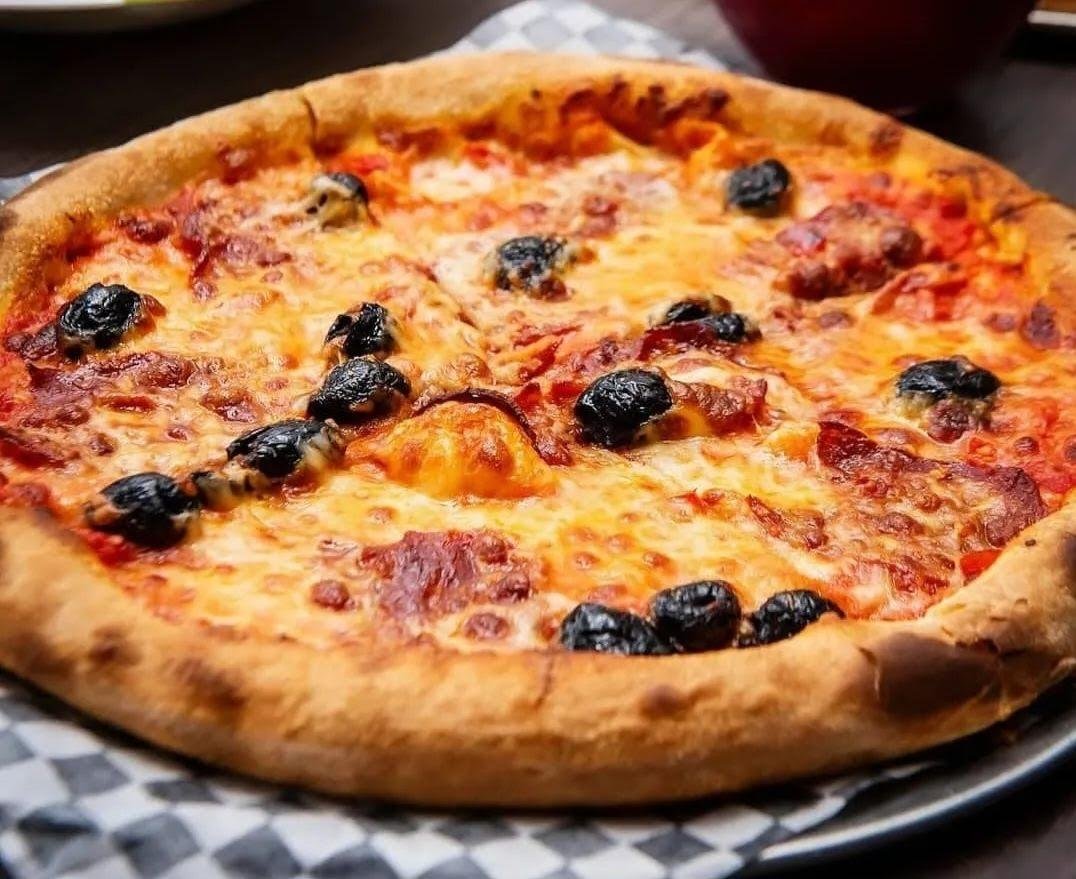 FBI Pizza pie with pepperoni and Moroccan black olives on checkered paper